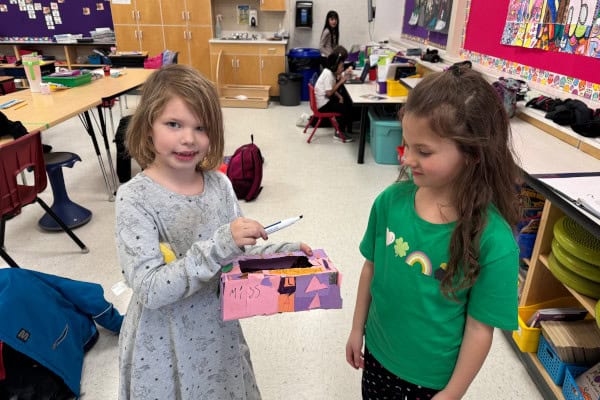 Linsford Park PIF Project 2025: 2 girls hold a marker collection box they decorated.