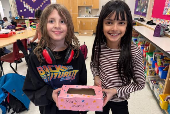Linsford Park PIF Project 2025: 2 girls hold a marker collection box they decorated.