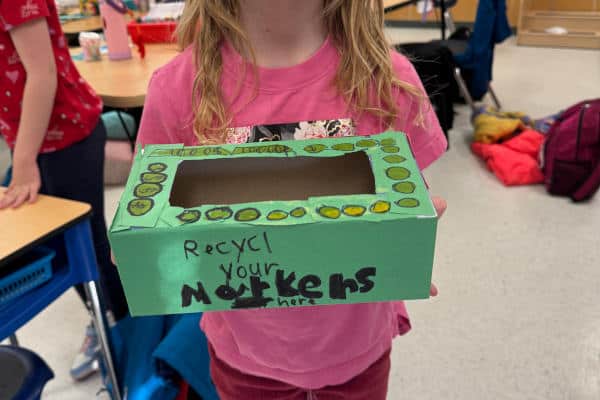 Linsford Park PIF Project 2025: A girl holds a marker collection box they decorated.